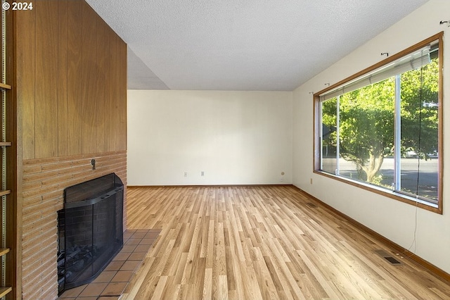 unfurnished living room featuring light wood-type flooring, a textured ceiling, and plenty of natural light