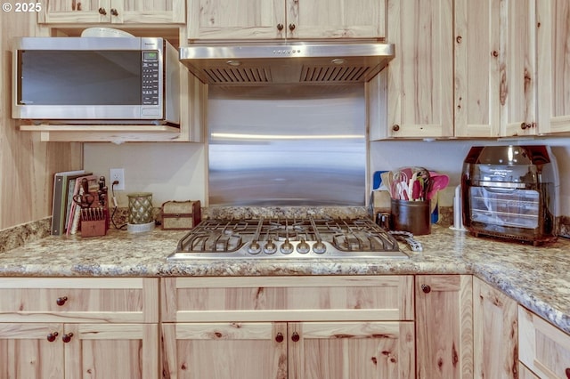 191 SW 67th St, Redmond, OR 97756 - kitchen with light stone counters, appliances with stainless steel finishes, under cabinet range hood, and light brown cabinetry