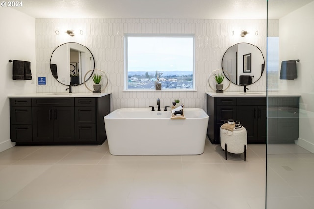 bathroom with a tub to relax in, vanity, and tile patterned floors