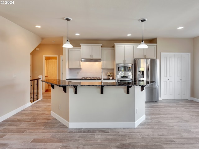 kitchen featuring appliances with stainless steel finishes, a kitchen island, a kitchen bar, and white cabinetry