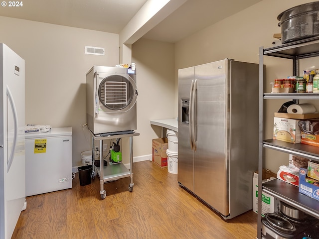 kitchen with fridge, washer / clothes dryer, light hardwood / wood-style floors, and stainless steel fridge with ice dispenser