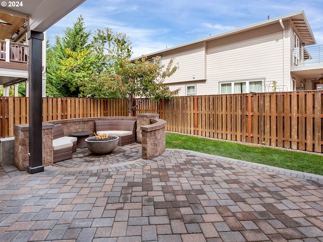 view of patio with an outdoor fire pit and a balcony