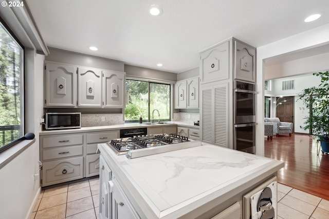 kitchen with sink, tasteful backsplash, light tile patterned floors, and appliances with stainless steel finishes