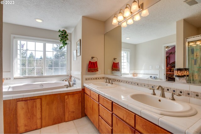 bathroom featuring tile patterned flooring, a tub, vanity, and a textured ceiling