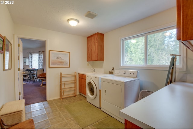 clothes washing area featuring a textured ceiling, cabinets, sink, and independent washer and dryer