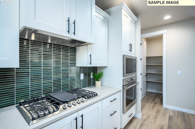 kitchen with light hardwood / wood-style floors, white cabinetry, stainless steel appliances, and tasteful backsplash