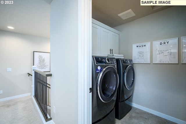 clothes washing area featuring washer and clothes dryer and cabinets