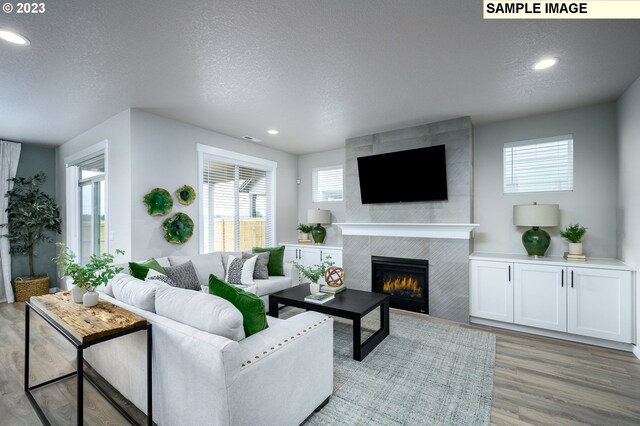 living room with a tile fireplace and light hardwood / wood-style flooring