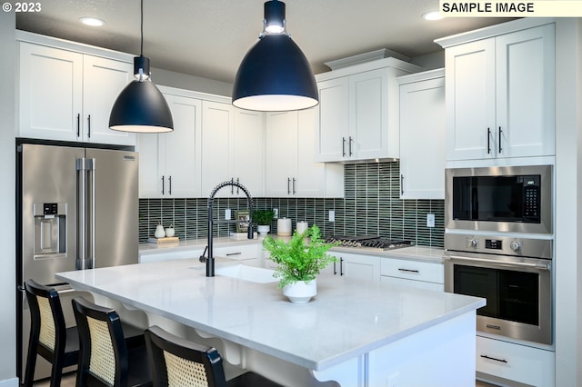 kitchen with pendant lighting, backsplash, a kitchen island with sink, and appliances with stainless steel finishes