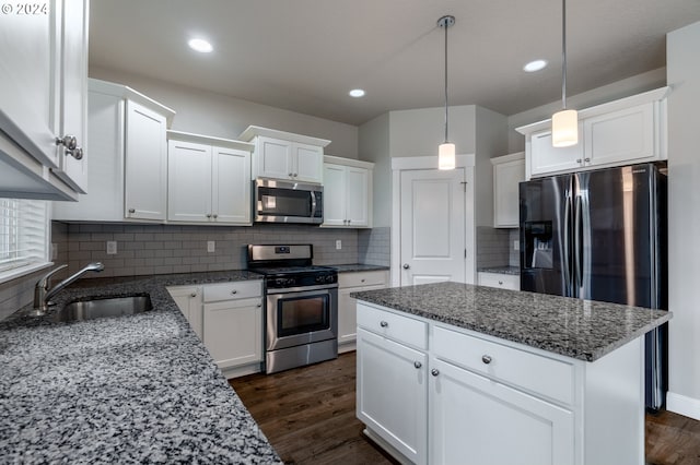 kitchen with appliances with stainless steel finishes, dark wood-style flooring, a center island, white cabinetry, and a sink