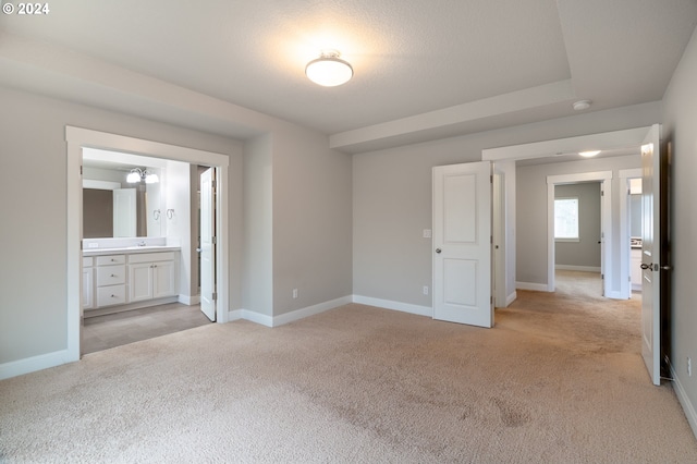 unfurnished bedroom with light colored carpet and ensuite bath