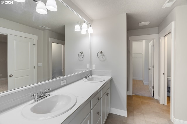 bathroom with tile patterned floors, vanity, a textured ceiling, and toilet