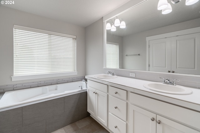 bathroom featuring tile patterned flooring, vanity, and a relaxing tiled tub