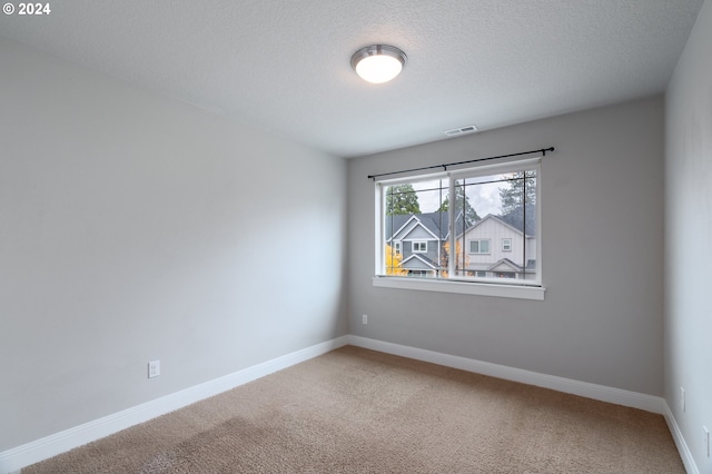 carpeted empty room with a textured ceiling, visible vents, and baseboards