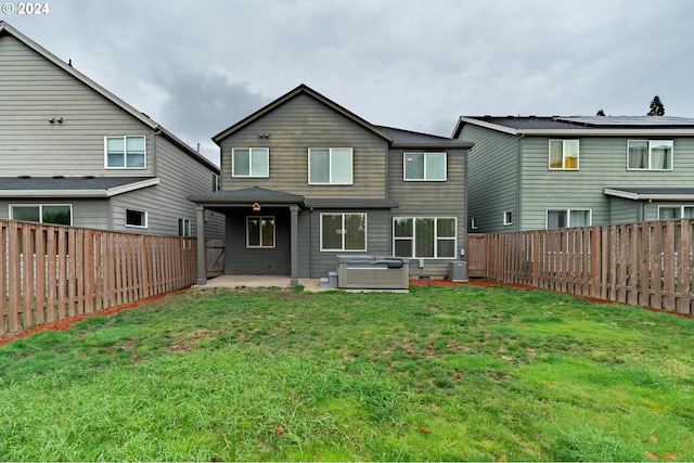 back of property with a patio area, a yard, and a hot tub