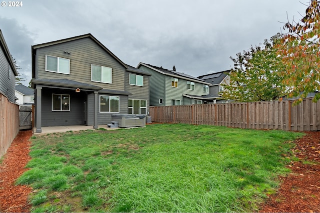 back of property with a lawn, a patio, and a hot tub