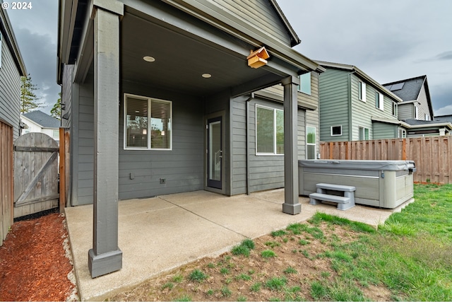 rear view of house with a gate, a patio, a hot tub, and fence