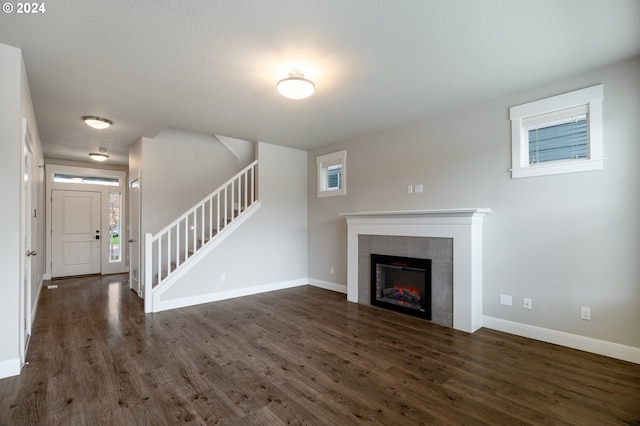 unfurnished living room featuring a fireplace, a wealth of natural light, stairway, wood finished floors, and baseboards