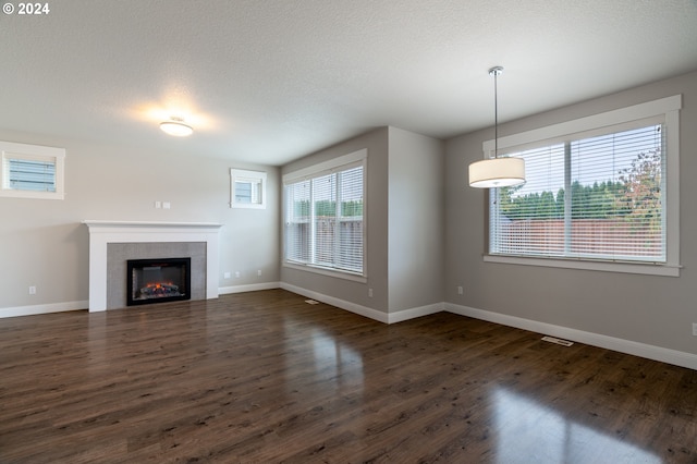 unfurnished living room with dark wood-style flooring, a tile fireplace, and baseboards