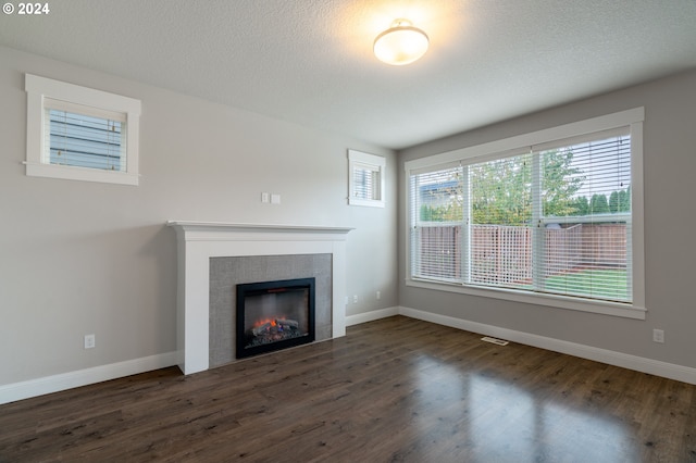 unfurnished living room featuring a fireplace, dark hardwood / wood-style flooring, and a textured ceiling