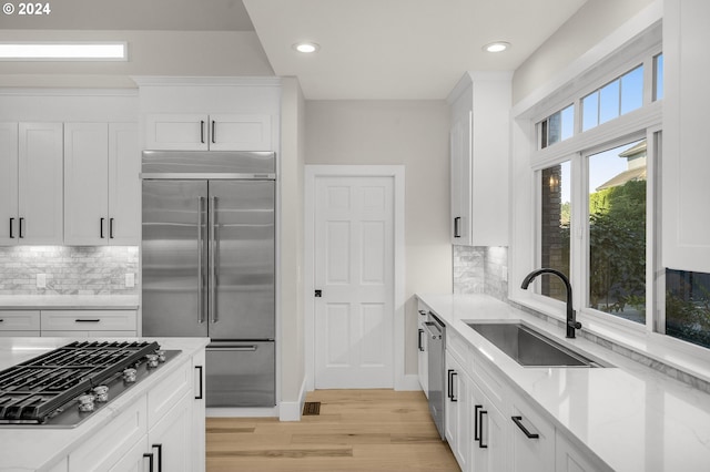 kitchen featuring appliances with stainless steel finishes, white cabinets, backsplash, and sink