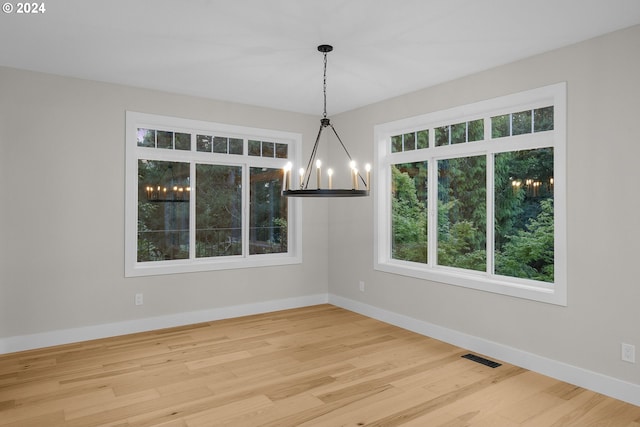 unfurnished dining area featuring a chandelier and hardwood / wood-style flooring