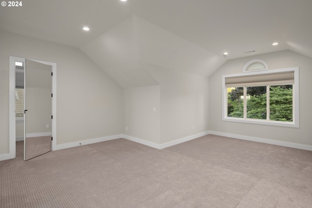 additional living space featuring light carpet and vaulted ceiling