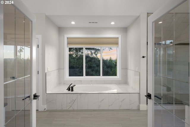 bathroom with tile patterned flooring and tiled tub