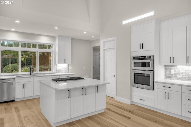 kitchen featuring sink, stainless steel appliances, white cabinets, and a center island