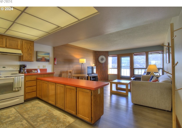 kitchen with a textured ceiling, hardwood / wood-style flooring, wood walls, kitchen peninsula, and white electric stove