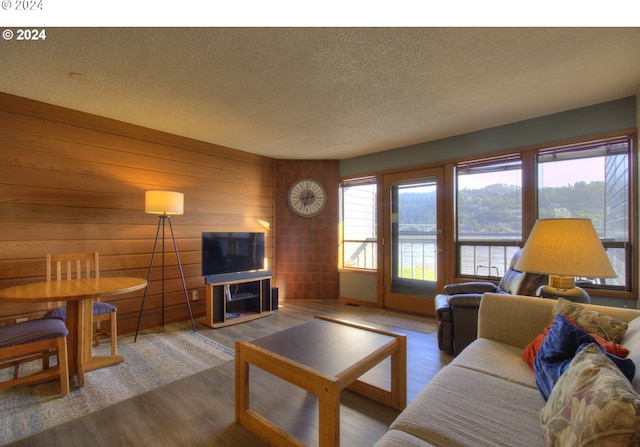 living room featuring wooden walls, a textured ceiling, and hardwood / wood-style floors