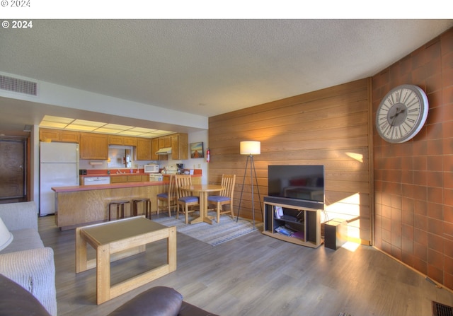 living room with wood-type flooring, wood walls, and a textured ceiling