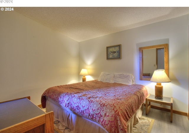 bedroom featuring a textured ceiling and light hardwood / wood-style flooring