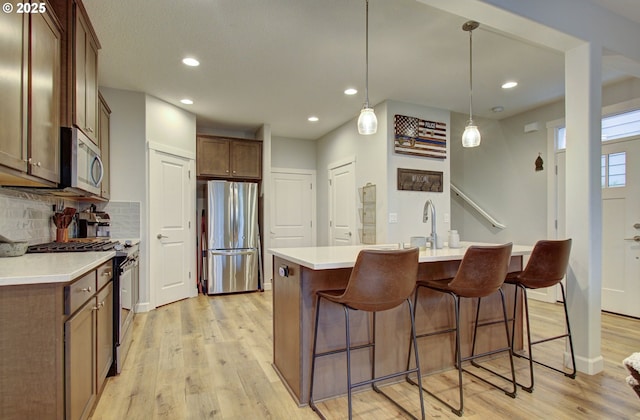 kitchen featuring backsplash, light wood-style flooring, light countertops, and appliances with stainless steel finishes