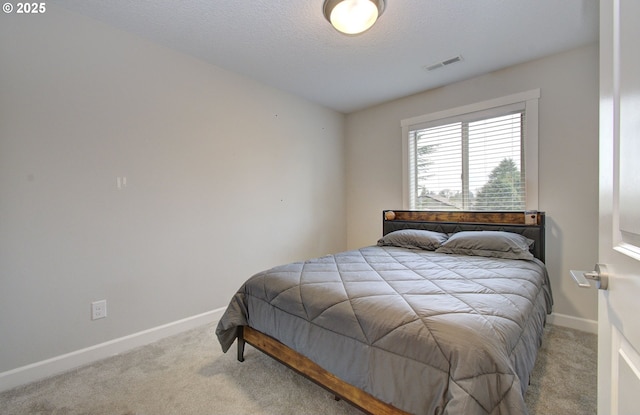 bedroom with baseboards, visible vents, carpet, and a textured ceiling