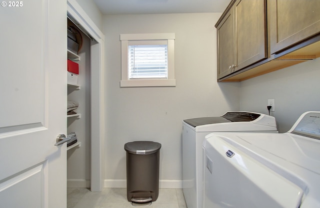 laundry area featuring washing machine and clothes dryer, cabinet space, baseboards, and light tile patterned flooring