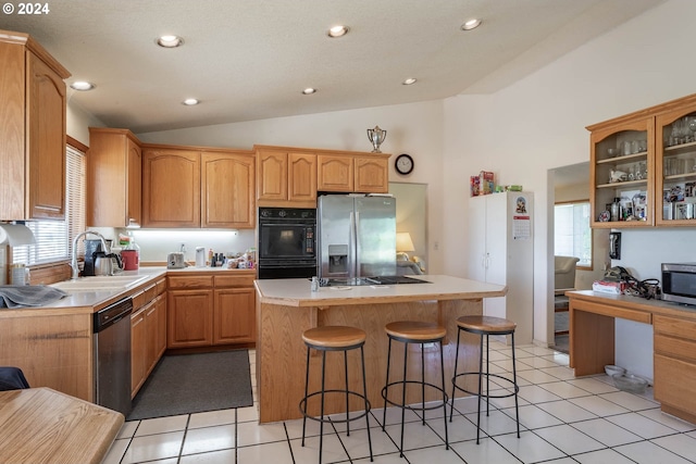 kitchen featuring sink, a kitchen bar, a center island, stainless steel appliances, and a healthy amount of sunlight