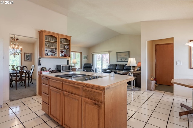 kitchen featuring lofted ceiling, light tile patterned floors, gas cooktop, a notable chandelier, and a kitchen island