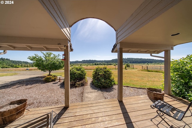 wooden deck with a rural view and a lawn