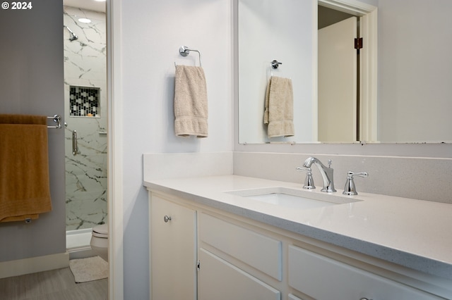 bathroom with tiled shower, vanity, and toilet