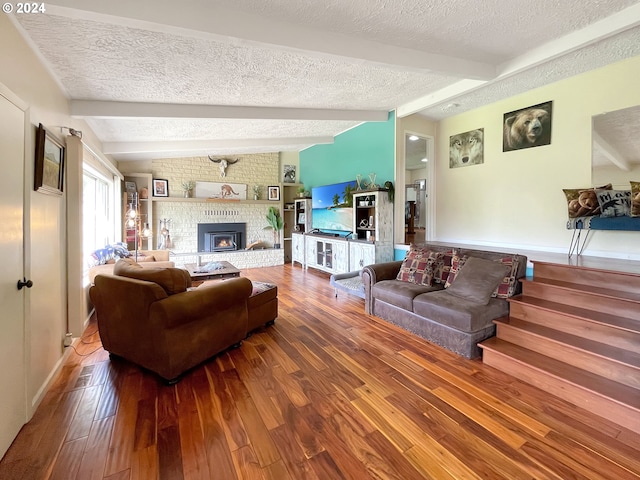 living room with a fireplace, hardwood / wood-style floors, a textured ceiling, and lofted ceiling with beams