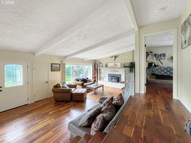 living room with hardwood / wood-style floors, lofted ceiling with beams, a large fireplace, and a textured ceiling