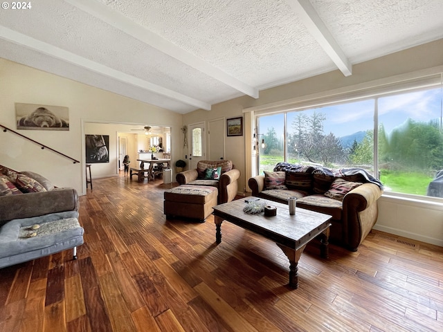 living room featuring vaulted ceiling with beams, ceiling fan, wood-type flooring, and a textured ceiling