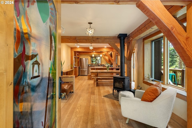 sitting room with beamed ceiling, track lighting, light hardwood / wood-style flooring, and a wood stove