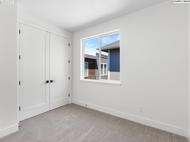 unfurnished bedroom featuring light carpet and a closet