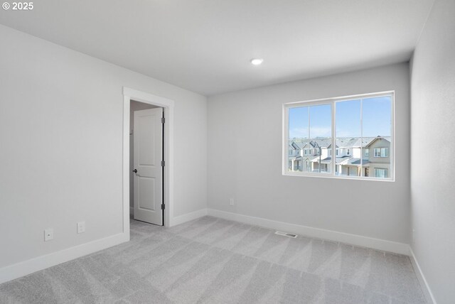 empty room with visible vents, light carpet, baseboards, and recessed lighting