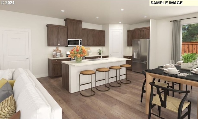 kitchen with sink, dark wood-type flooring, a kitchen breakfast bar, a center island with sink, and stainless steel fridge with ice dispenser