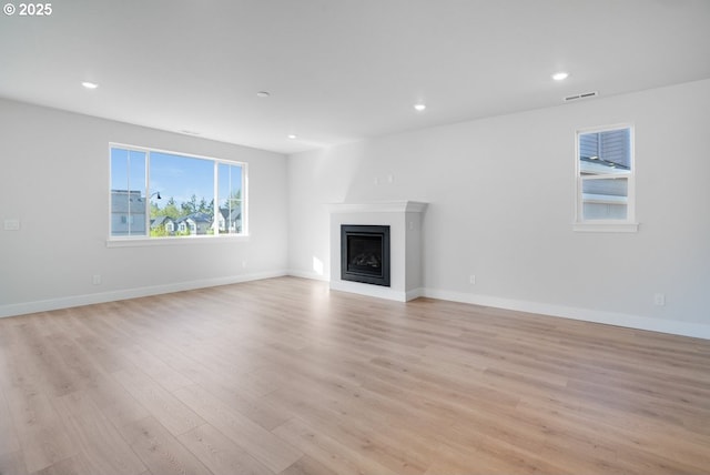 unfurnished living room with baseboards, visible vents, recessed lighting, light wood-style floors, and a fireplace