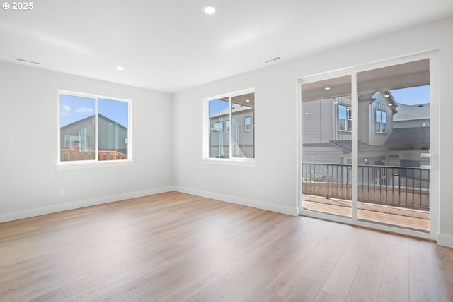 spare room featuring baseboards, wood finished floors, and visible vents