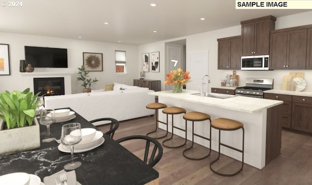 kitchen featuring dark wood-type flooring, a breakfast bar area, stainless steel appliances, dark brown cabinetry, and an island with sink